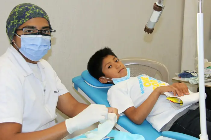 Niño sonriendo en el sillón dental mientras la odontóloga lo revisa