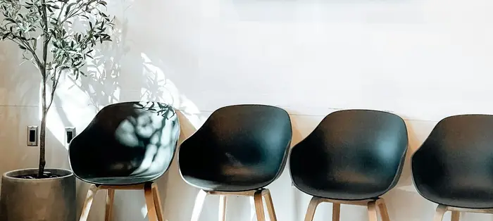 Sala de espera con sillas negras y un olivo